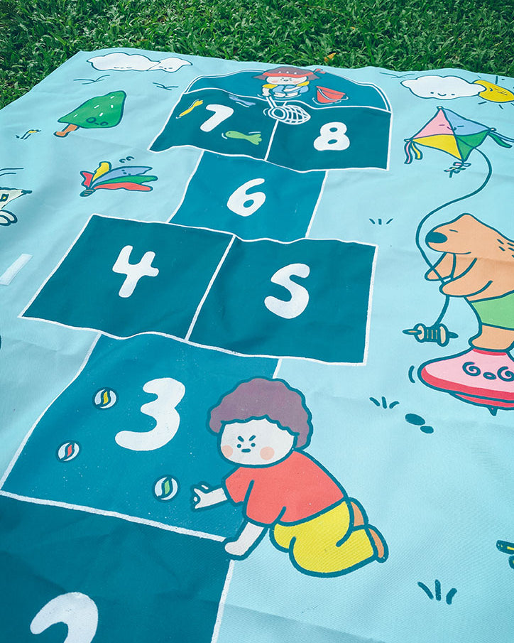 Children's hopscotch mat with illustrations and numbers on a grassy background