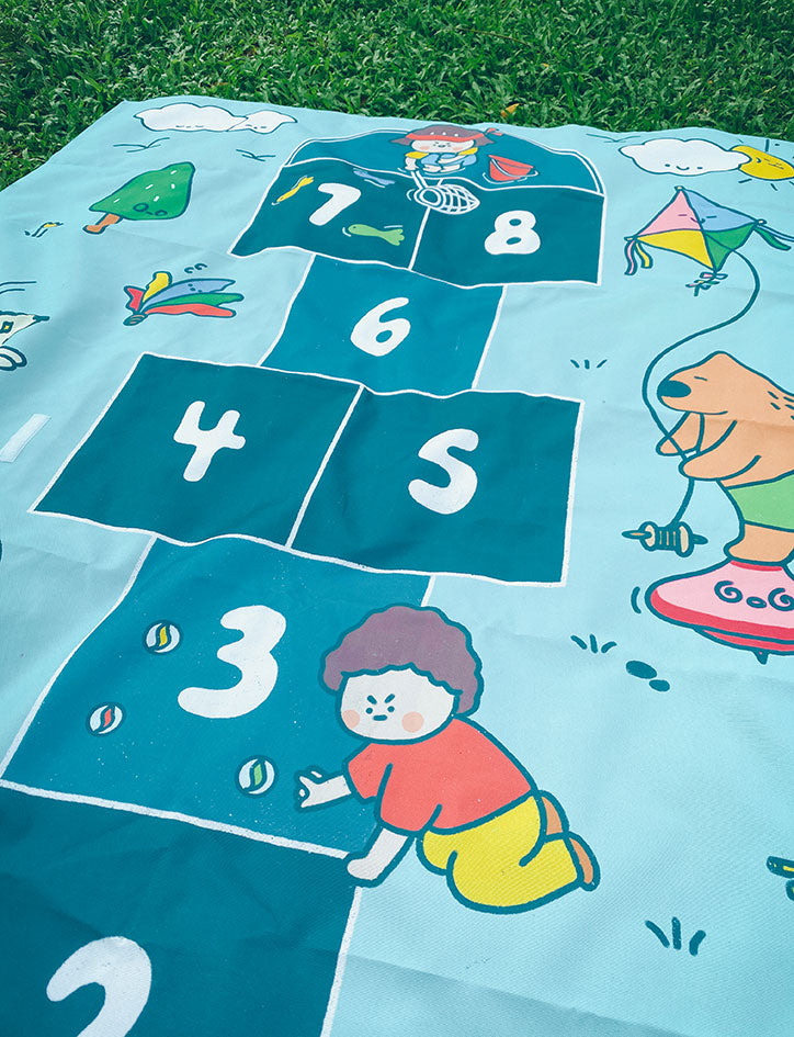 Children's hopscotch mat with illustrations and numbers on a grassy background